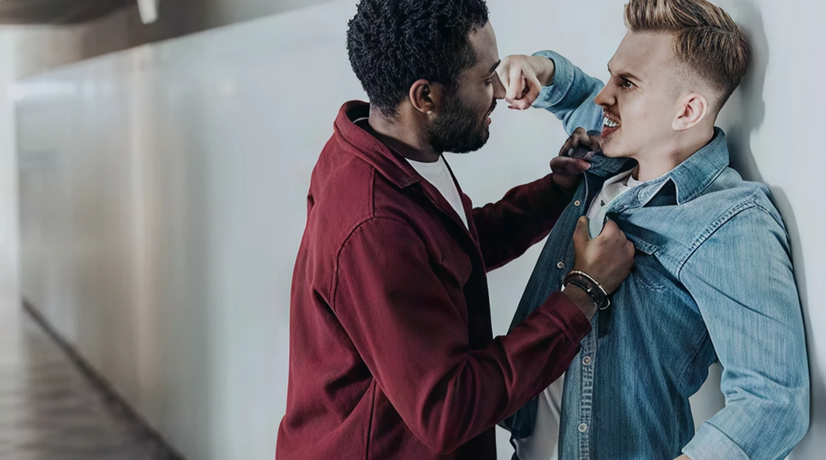 Two men are engaged in a physical fight in a narrow hallway.