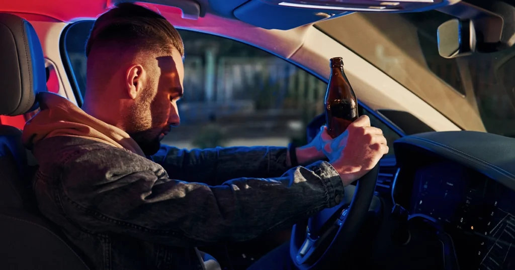 DUI vs DWI: Man holding alcohol while driving