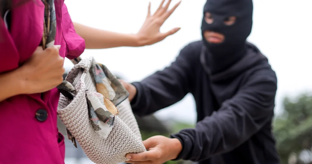 Masked thief attempting to steal a purse from a woman.