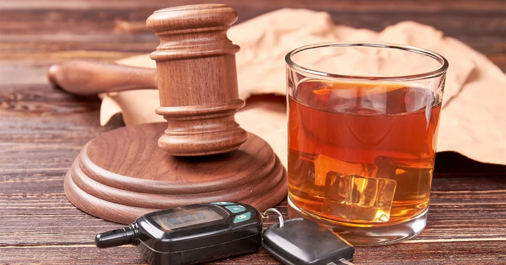 Glass of alcohol, gavel, and car keys representing DUI charges.