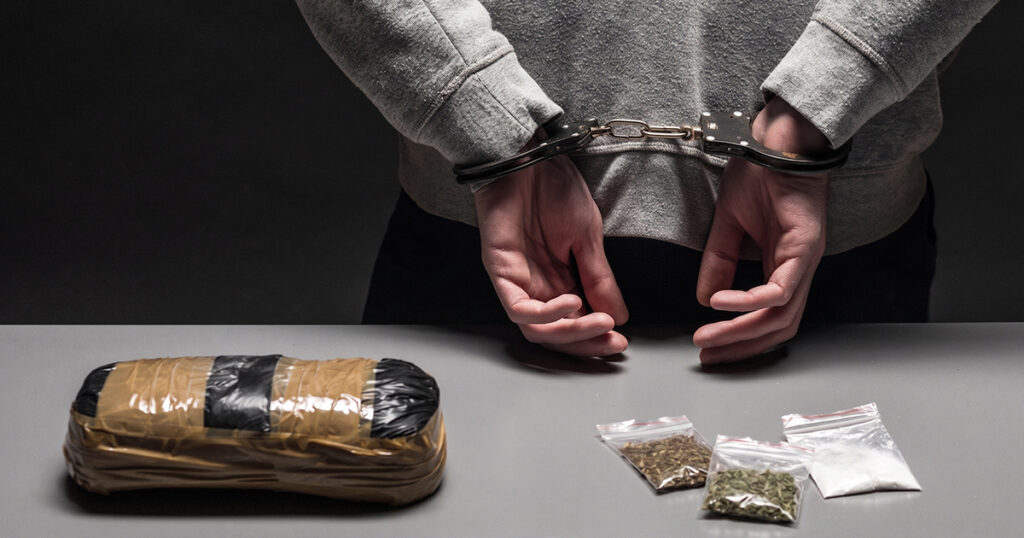 Handcuffed suspect with seized drug evidence