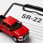 A red toy pickup truck sits on a clipboard holding an SR-22 form, photographed in a clean studio setting.