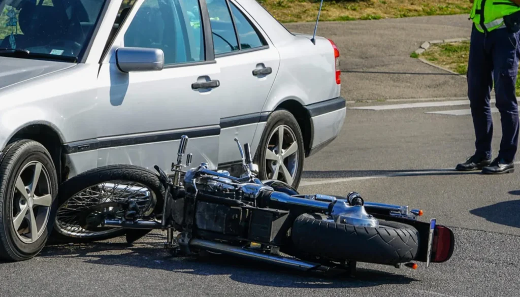 Motorcycle lying on its side after colliding with a car