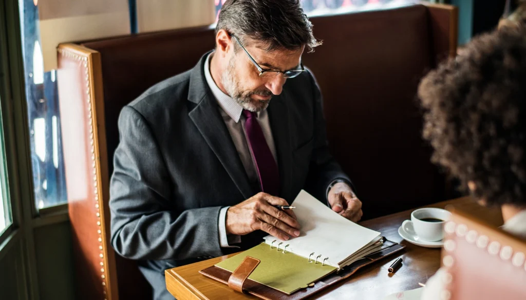 Lawyer reviewing document with pen at table during coffee meeting.